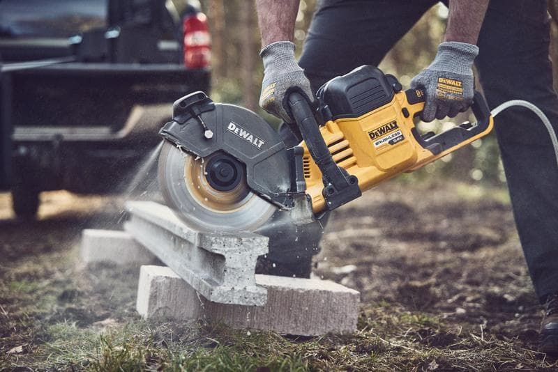 DEWALT Säge schneidet draußen Beton, Bediener trägt Handschuhe zur Sicherheit.