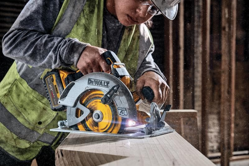 DEWALT Akku-Kreissäge schneidet Holz, von einem Arbeiter mit Weste auf einer Baustelle verwendet.