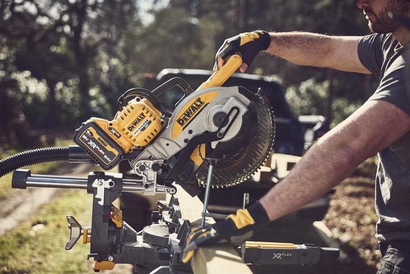 Person sägt Holz im Freien mit einer kabellosen DEWALT Gehrungssäge, gelb-schwarz, XR FLEXVOLT Akku.