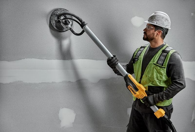 Arbeiter nutzt DEWALT DWE7800, DWE7800-QS Wandschleifer an Trockenwand. Fotografieprodukt.