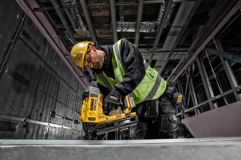 Arbeiter nutzt DEWALT DCN890P2 Nagler auf Baustelle, trägt Helm und Sicherheitsweste.