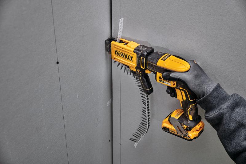 DEWALT DCF6202 Schraubgerät schraubt Trockenbau, gehalten von einer behandschuhte Hand.