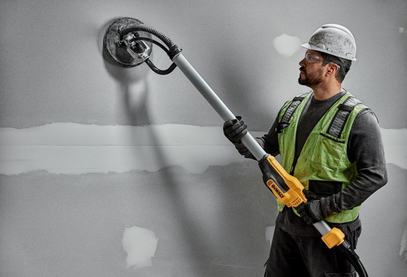 Arbeiter nutzt DEWALT DWE7800, DWE7800-QS Wandschleifer an Trockenwand. Fotografieprodukt.